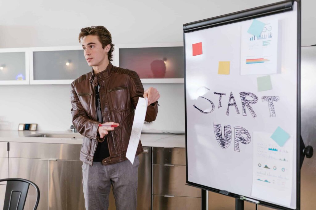 Vīrietis brunā ādas jakā prezentē savu start up ideju